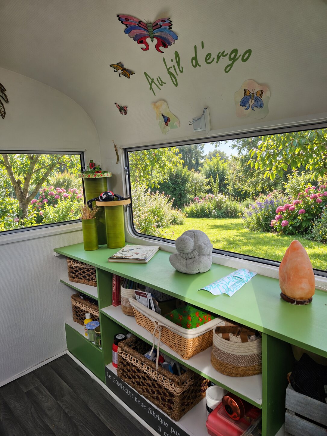 L'intérieur de la caravane thérapeutique Au fil d'Ergo : étagères de matériel créatif face au jardin